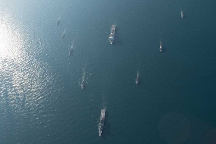 shutterstock_2766462157.jpg Aerial view of multiple naval ships navigating in the ocean