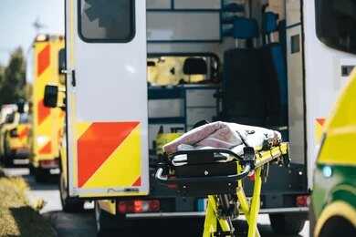 Ambulance with open rear doors and an empty stretcher outside