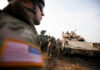 Pentagon Pullback? Lithuania Sounds the Alarm Soldiers in military gear coordinating near armored vehicles during training