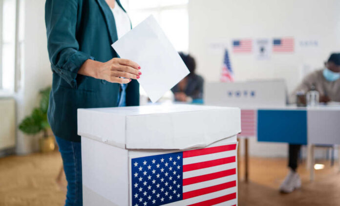 shutterstock1823718650jpg A person casting a vote into a ballot box at a polling station