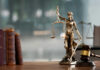 Ohio Strikes Back — Parental Consent Returns A bronze statue of Lady Justice holding scales and a sword, with law books and a gavel in the foreground