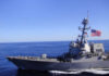 Hormuz Tinderbox: Trump Promises “Very Hard” Hits A naval destroyer sailing in the ocean with an American flag
