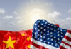 FBI Bombshell: Reporter Ran Beijing Playbook Crumpled flags of the United States and China against a cloudy sky