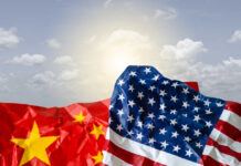 FBI Bombshell: Reporter Ran Beijing Playbook Crumpled flags of the United States and China against a cloudy sky