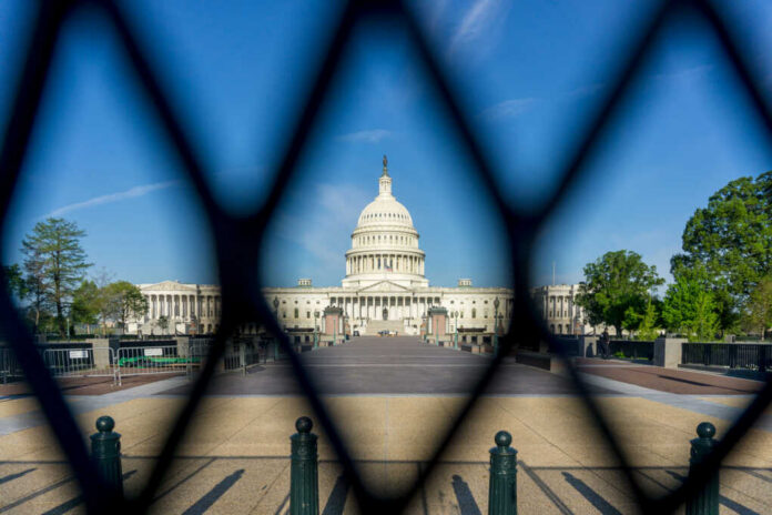 shutterstock_1959169297-1 View of the U.S. Capitol building through a security fence
