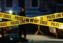 Phone Theft Turns Deadly — City Erupts Police tape marking a crime scene with blurred figures in the background