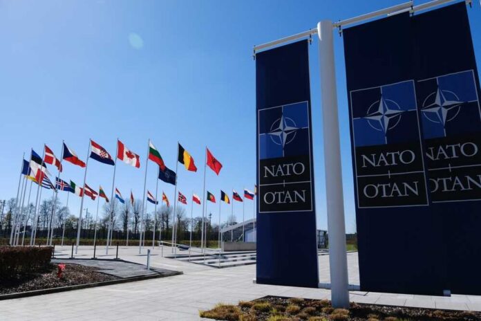 The,National,Flags,Of,Countries,Member,Of,The,Nato,Fly Flags of various nations displayed outside NATO headquarters under a clear blue sky