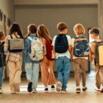 170,000 Kids Vanish? Where’d They Go? A group of children walking together in a school hallway, each carrying a backpack