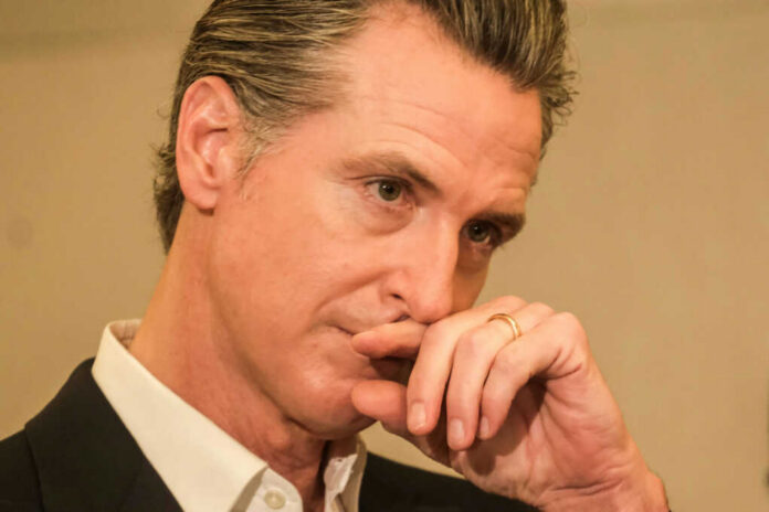 shutterstock_2368126879 Close-up of a man in a suit with a thoughtful expression, hand on chin