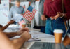 Noncitizen Voting Shock Hits New Jersey People participating in a voting event with American flags and paperwork