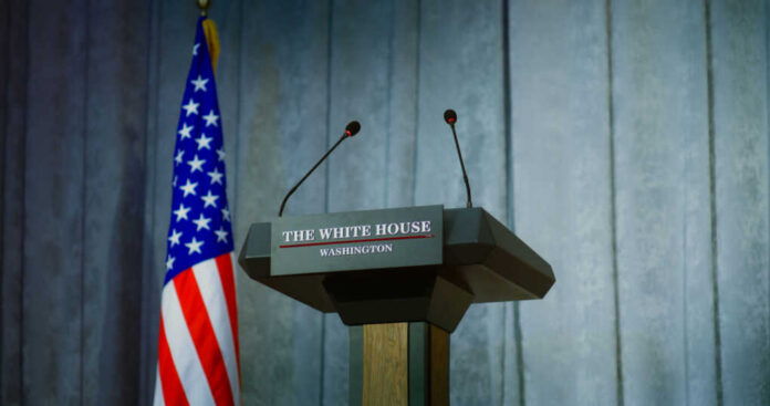 shutterstock_2448402565 Press podium with microphones and American flag in the background