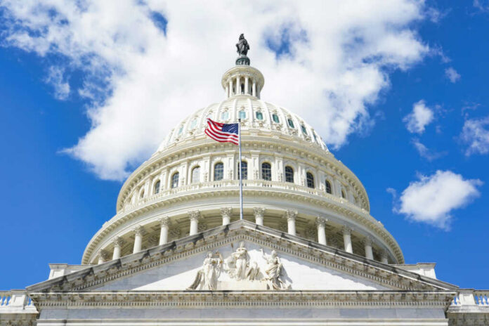 The U.S. Capitol building with an American flag flying in front against a blue sky