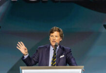 A man in a suit speaking at a podium with a microphone