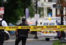 Police officers near a crime scene marked by caution tape