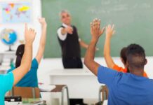 Schools vs. Parents Erupts Over ‘Adultism’ Push Students raising hands in a classroom while teacher points