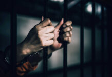 Gen Z Chatroom Labeled Extremist Network Hands gripping prison bars in a dimly lit environment