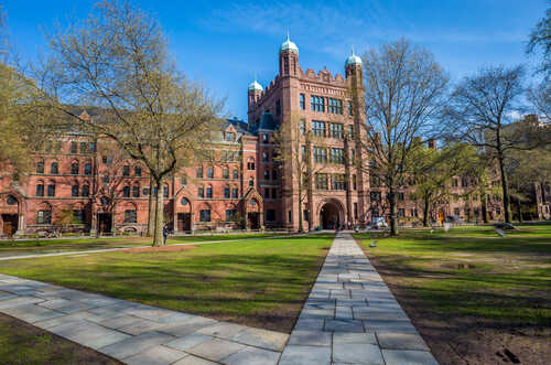 Yale,University,Buildings,In,Spring,Blue,Sky,In,New,Haven, Historic university building surrounded by trees and a pathway