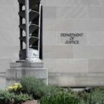 Department of Justice building exterior with stone facade and plants