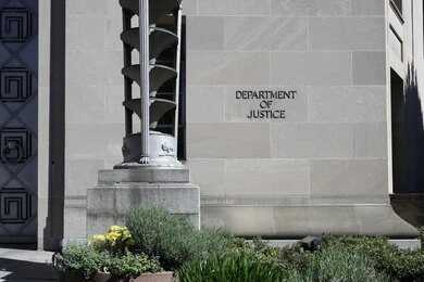 shutterstock_2154432275 Department of Justice building exterior with stone facade and plants