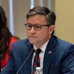 DSA Bombshell Claims Ignite Firestorm man in a blue suit speaking into a microphone at a meeting
