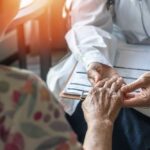 France’s Chilling New Line: Who Decides Life? A doctor holding the hand of an elderly patient during a consultation