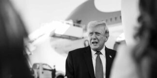A political figure speaking outdoors in front of an airplane