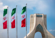 Shadow Deal Hints at Tehran Shake-Up Three Iranian flags in front of the Azadi Tower against a blue sky