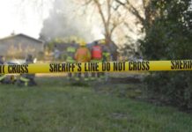 Stolen Bike Showdown Turns Deadly Yellow police tape marking a restricted area at a fire scene with firefighters in the background