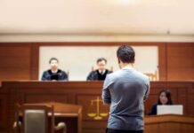 defendant stands before judges in a courtroom