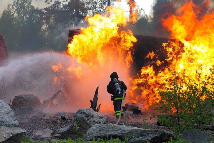 Firefighter,Trying,To,Put,Water,On,A,Big,Fire Firefighter battling a large fire with water spray