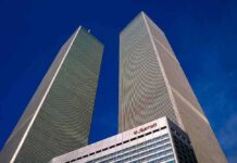 Twin rectangular skyscrapers rising above a hotel facade against a clear blue sky