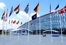 Putin Probe Rumors—Trump Brushes Off Danger Row of national flags outside a modern glass building