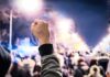 Raised fist in front of a large crowd at night