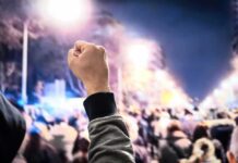 Rally For Accused Mom Stuns Nation Raised fist in front of a large crowd at night