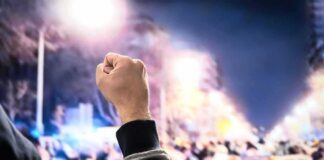 Raised fist in front of a large crowd at night