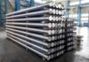 Stacked metal rods on pallets in an industrial warehouse