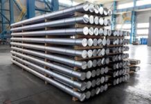 Stacked metal rods on pallets in an industrial warehouse