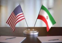 Compensation Gambit Rattles Iran Talks United States and Iran desk flags on a stand