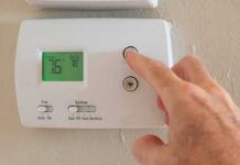 Hand adjusting a digital thermostat on a wall