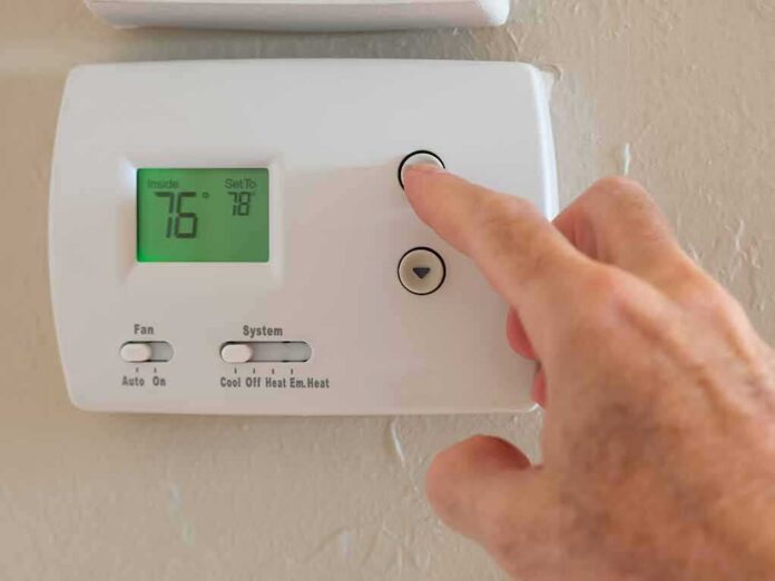 Hand adjusting a digital thermostat on a wall