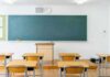 Empty classroom with desks facing a large chalkboard
