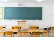 Empty classroom with desks facing a large chalkboard