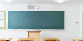 Empty classroom with desks facing a large chalkboard