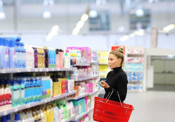 Woman shopping in a supermarket aisle with a red basket