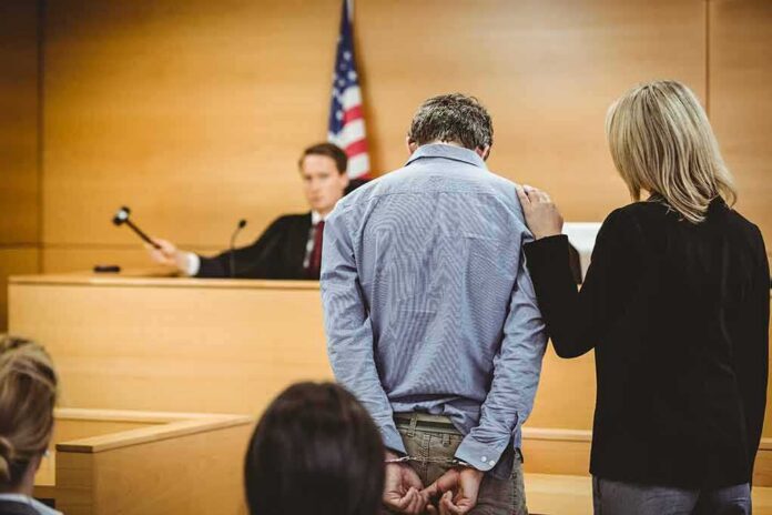 Defendant in handcuffs stands before a judge in a courtroom