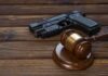Gun Buffer Around Synagogues Blocked Gavel and handgun on wooden table