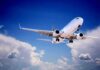 Commercial airplane flying with landing gear extended against a blue sky