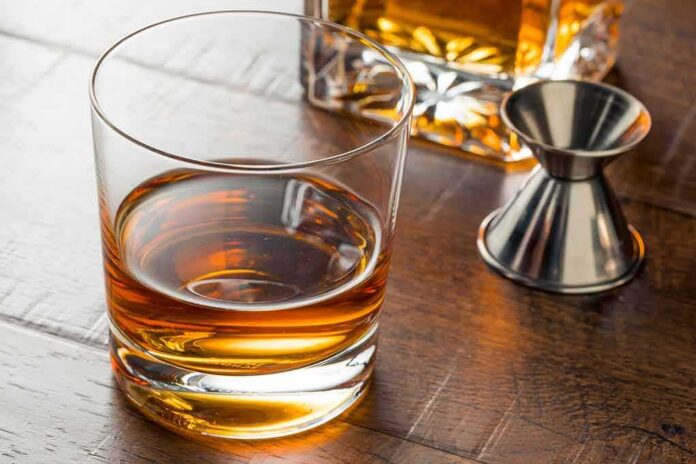 shutterstock_1062399677 Whiskey in a rocks glass on a wooden table