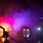 Gas Pump Showdown Stuns Suburb Handcuffs on a surface with police cars and flashing lights in smoky darkness
