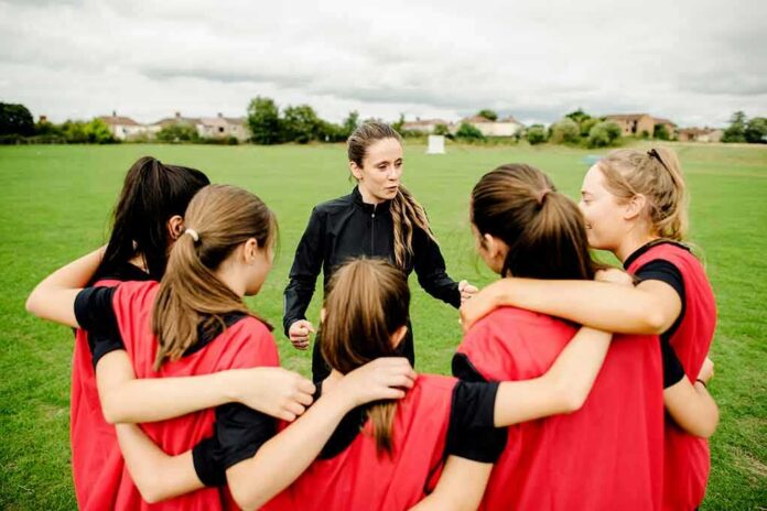 Coach talks to youth team in a huddle on a field